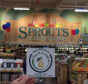 A F2E label held up against the Sprouts Market sign