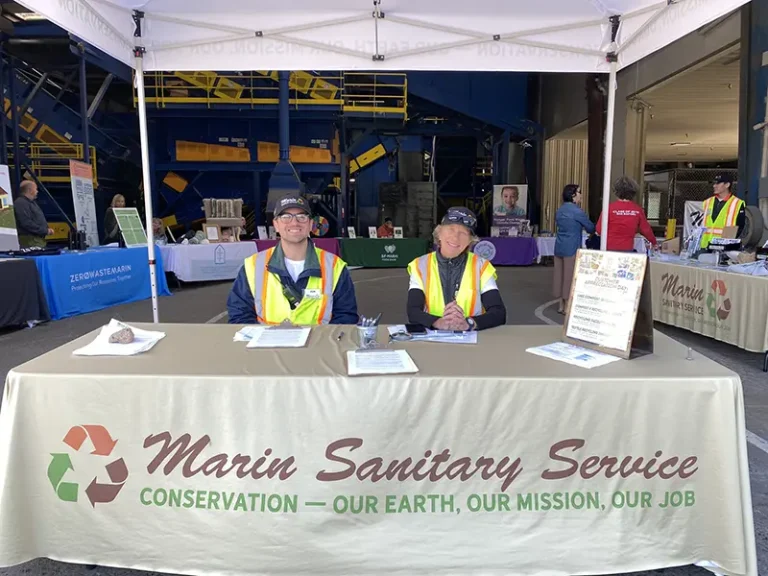 MSS employees smile sitting at a booth during Customer Appreciation Day